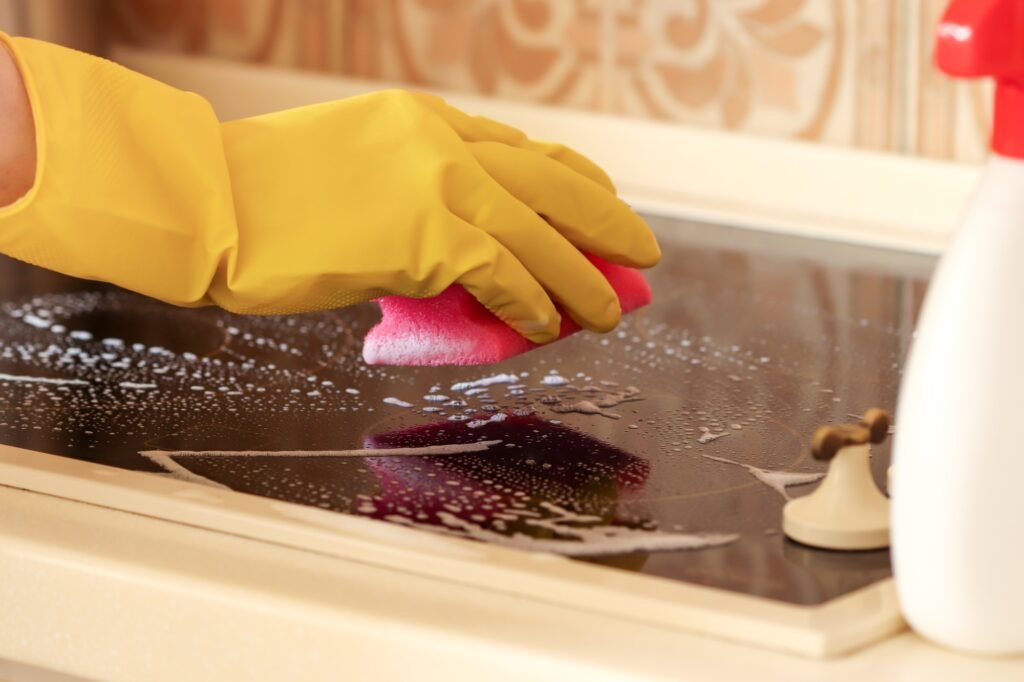 A woman washes the hob of an electric stove with detergent. cleaning the house